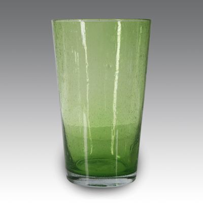 le verre vert est posé sur la table devant un fond gris