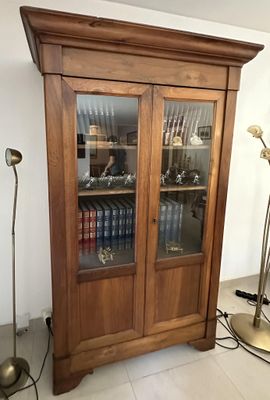 a tall wooden cabinet with many books on it