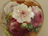 a green vase with flowers painted on it on a table