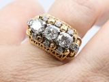a man ' s hand holding a gold and diamond ring