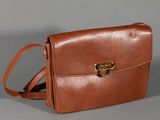 brown leather handbag with gold buckles on a grey background