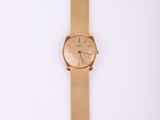 gros plan d'une montre-bracelet en or sur une surface blanche
