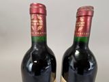 two bottles of red wine sitting next to each other on a table