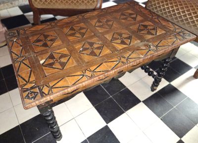 une table avec un plateau en bois posée sur un sol à damier noir et blanc