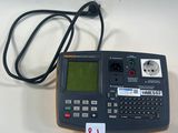 une calculatrice posée sur une table, à laquelle est relié un cordon