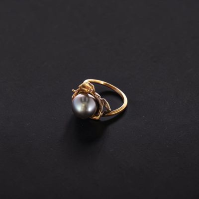 a gold and pearl ring on a black surface