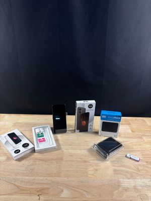 Plusieurs appareils électroniques sont posés sur une table en bois, sur fond noir.