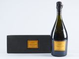 the bottle of champagne is next to a black box on a white surface