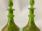 une paire de bougeoirs en verre vert ornés de motifs dorés