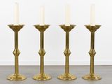 three tall brass candlesticks with white candles sitting on top of each other