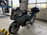 a black motorcycle parked in a garage with a car in the background