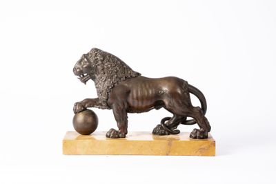 statue en bronze représentant un lion tenant une balle, posée sur un socle en marbre