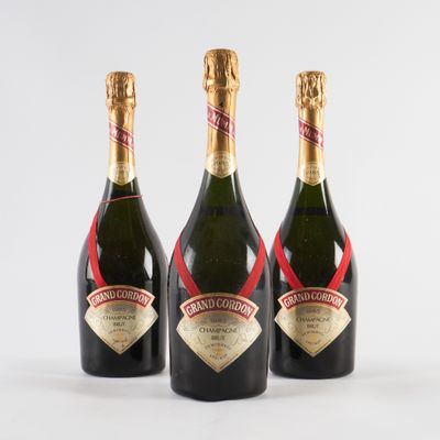 trois bouteilles de champagne sont alignées sur une surface blanche