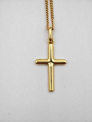 un pendentif en forme de croix en or, suspendu à une chaîne en or, sur fond blanc