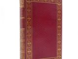 un vieux livre à la couverture rouge posé sur une surface blanche