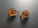 une paire de boucles d'oreilles en or ornées de grenats sur un fond noir
