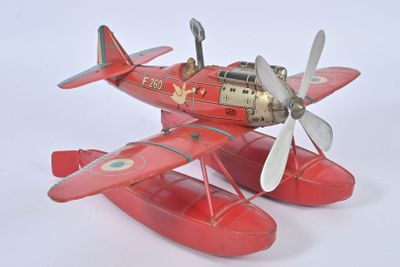un petit avion rouge avec une hélice, posé sur une surface blanche