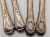 three silver spoons and two silver spoons on a white surface