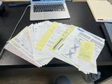 a laptop computer sitting on a desk next to a pile of papers
