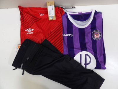 un maillot de foot violet et rouge et un pantalon noir posés sur une table blanche