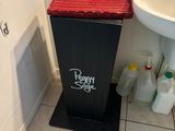 a trash can in the corner of a bathroom next to a sink