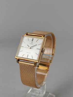 un gros plan d'une montre en or posée sur un socle transparent