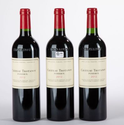 trois bouteilles de vin rouge posées l'une à côté de l'autre sur une surface blanche
