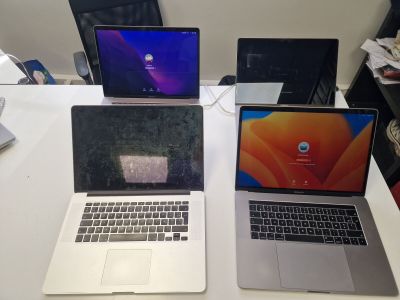 three laptops sitting on a table with a mouse on top of them