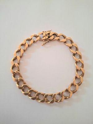 an image of a gold bracelet on a white surface