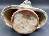 a close up of a clay vase with a face on it