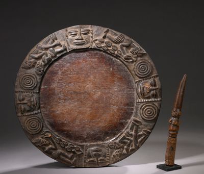 une image représentant une assiette en bois ornée de sculptures, à côté d'un couteau