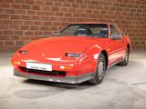 an image of a red sports car parked in front of a brick wall