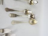 a lot of silver spoons and forks laid out on a table