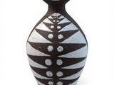 un vase noir et blanc posé sur une surface blanche