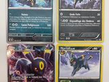 Quatre cartes Pokémon sont posées sur une table avec un fond blanc.