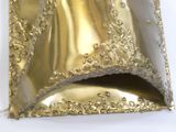 un sac à main doré posé sur une surface blanche