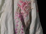 a close up of a white dress with pink flowers on it