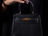 a woman holding a black handbag in her hands