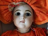a doll with an orange dress and a big hat