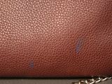 brown leather handbag with chain strap on table in room