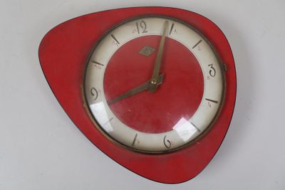 une horloge rouge au cadran blanc accrochée à un mur blanc