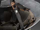 an old black helmet with a leather strap and a metal buckle