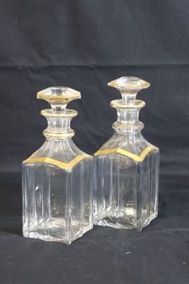 deux bouteilles en verre transparent ornées de bordures dorées sur fond noir
