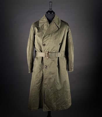 un trench-coat vert posé sur un mannequin, sur fond noir