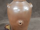 a brown vase sitting on top of a bowl on the ground