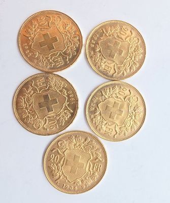 quatre pièces d'or sont disposées en ligne sur une surface blanche