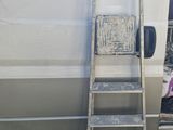 a ladder leaning against a white van with a picture on it