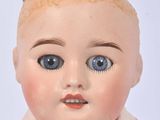 a close up of a doll with blue eyes and a pink shirt