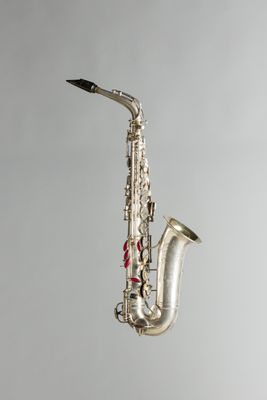 un saxophone argenté suspendu à une ficelle sur un mur gris