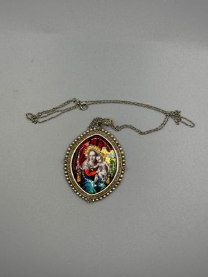 un gros plan sur un collier orné de la photo d'une femme tenant un enfant dans ses bras
